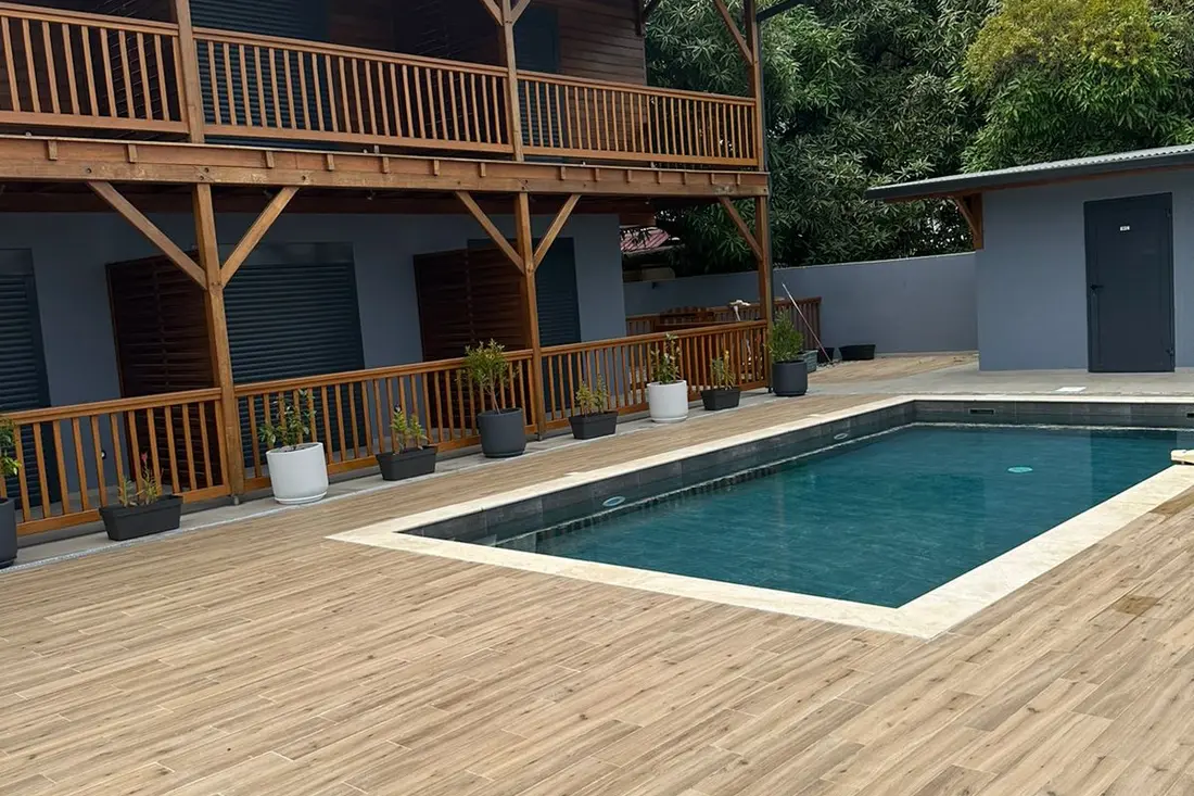 Piscine de la Résidence Francis à Montabo : bassin bordé de travertin, terrasse en bois et coursives à balustrades