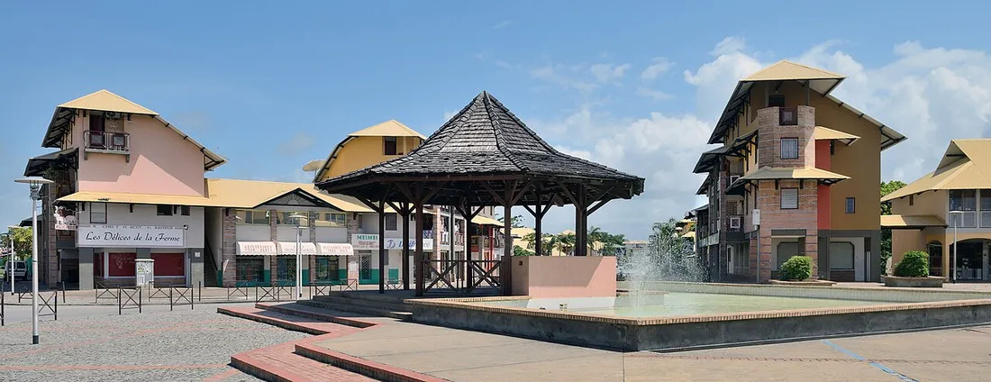 Centre-ville de Kourou en Guyane, place avec carbet et immeubles de logements au-dessus des commerces