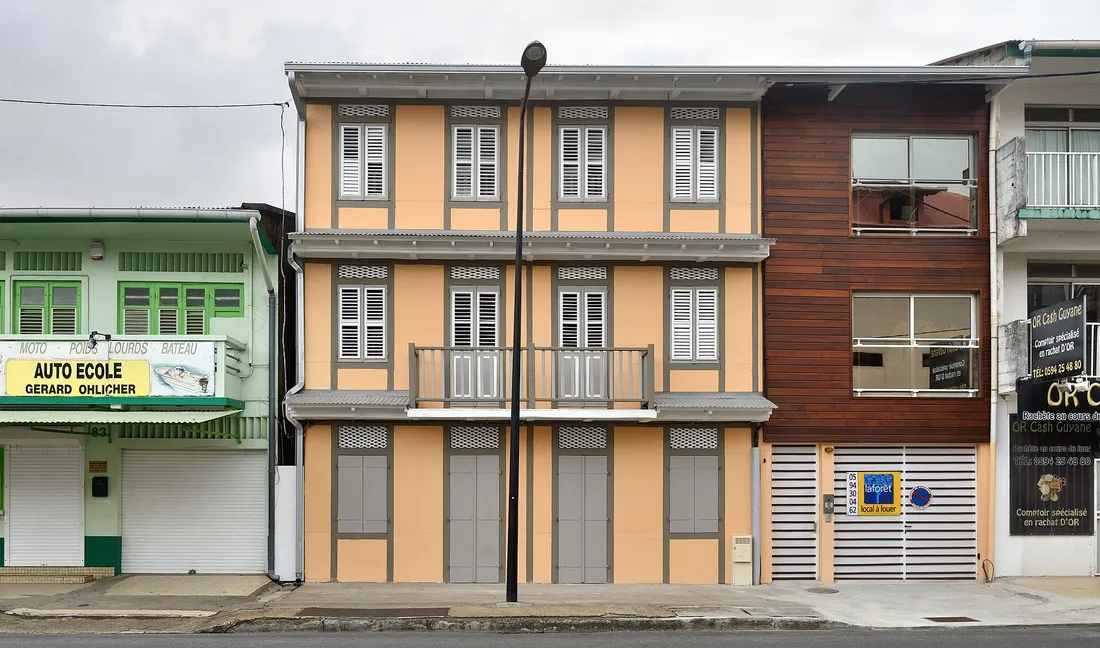 Maison créole rénovée à Cayenne avec panneau « local à louer », façade à volets sur rue en Guyane