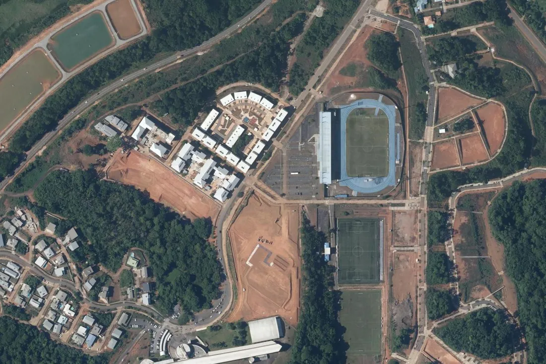 Vue aérienne verticale de l'écoquartier Georges Othily à Rémire-Montjoly : au centre la plateforme terrassée du collège, à gauche les immeubles neufs du quartier, à droite le stade et les terrains de sport