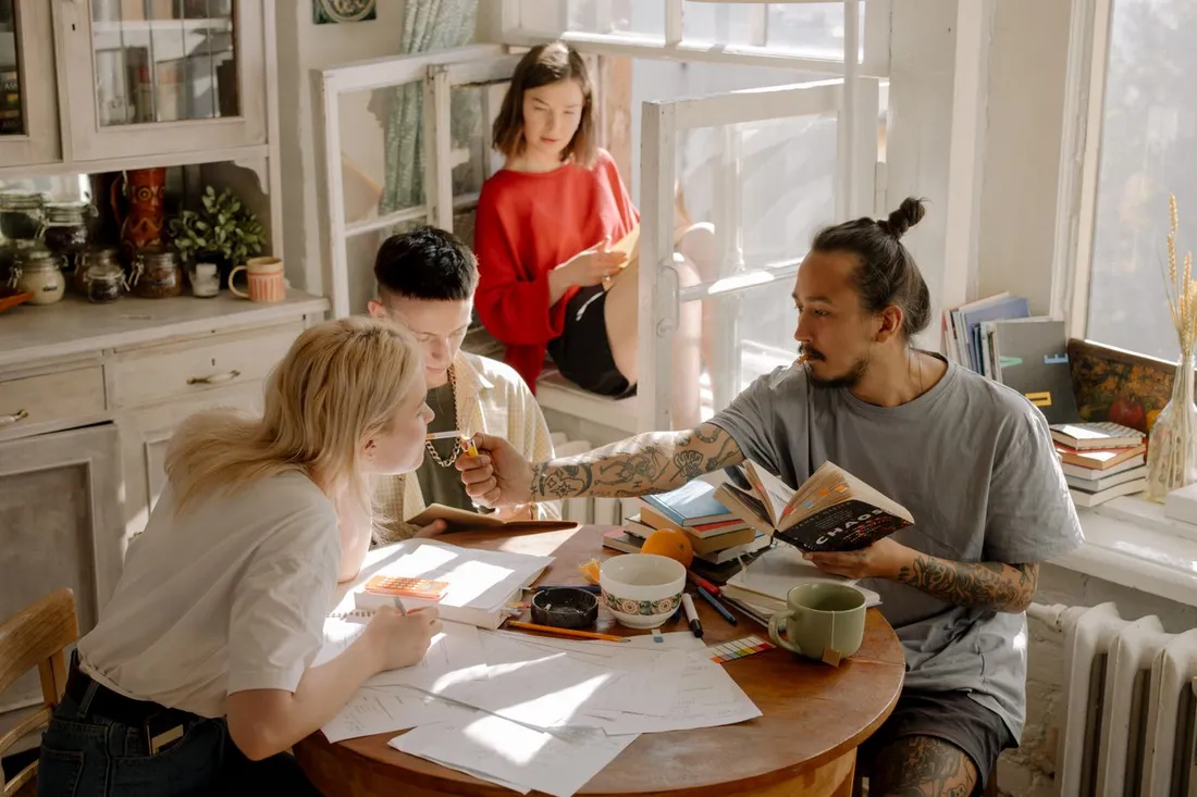 Jeunes colocataires étudiants et actifs travaillant ensemble autour d'une table dans un appartement lumineux