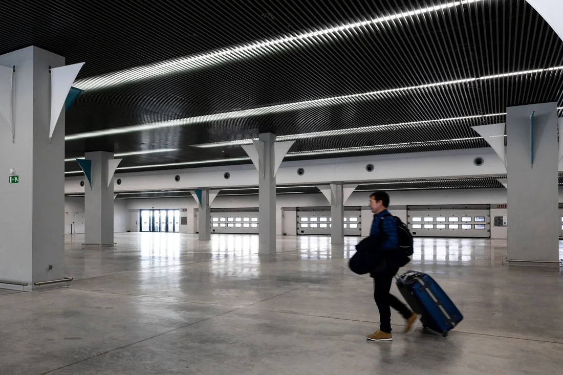 Voyageur traversant un hall d'aéroport moderne et dégagé avec ses bagages