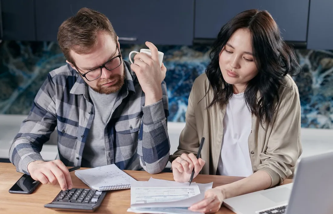 Couple etablissant son budget mensuel du foyer avec calculatrice, factures et ordinateur portable