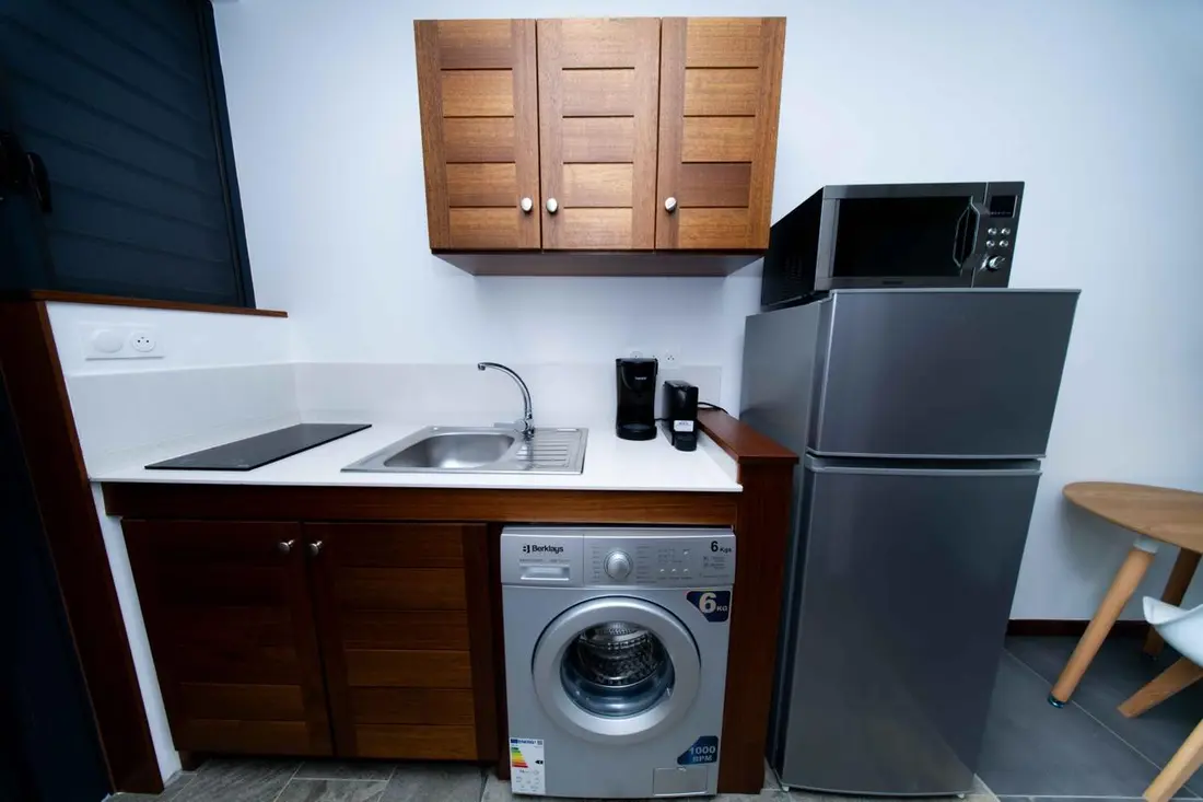 Kitchenette du Baduel Smart Studio avec placards en bois, lave-linge et réfrigérateur