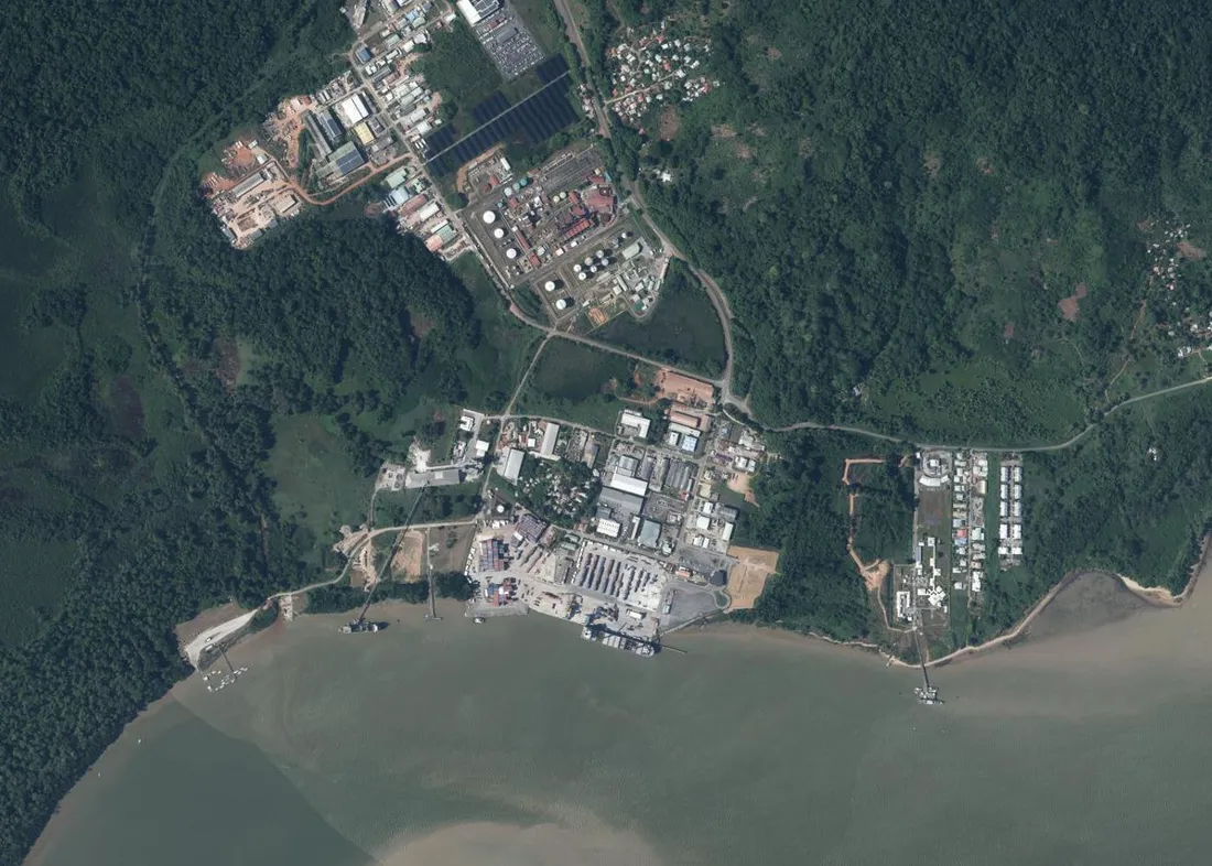 Vue aérienne verticale du lieu-dit Dégrad-des-Cannes à Rémire-Montjoly : la centrale thermique et ses réservoirs en haut, le port de commerce et ses quais au centre, l'emprise de la base navale à droite au bord du Mahury