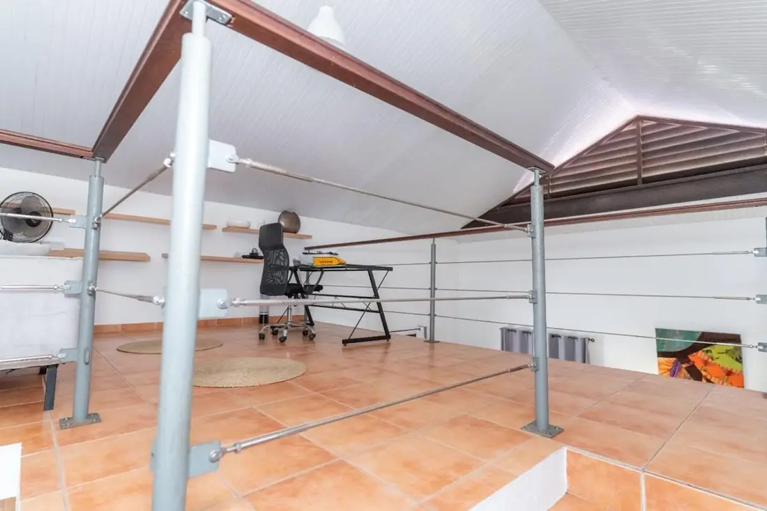 Mezzanine de la Casa Belas Artes : bureau et fauteuil sous la charpente, garde-corps à câbles