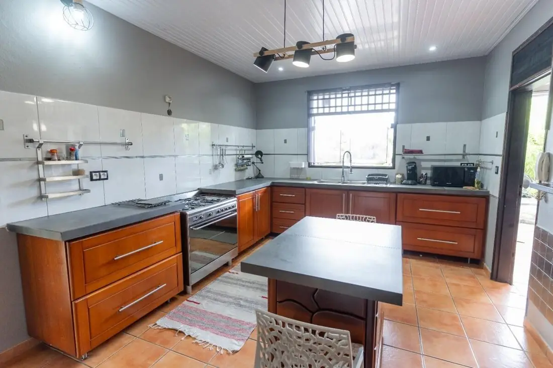 Grande cuisine de la Casa Belas Artes : piano de cuisson, îlot central et meubles en bois