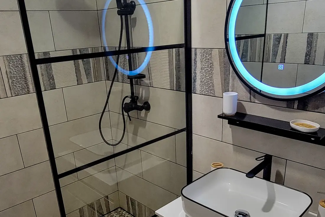 Chambre d’un appartement Cayenne Chic : lit fait, chevets éclairés et climatisation au mur