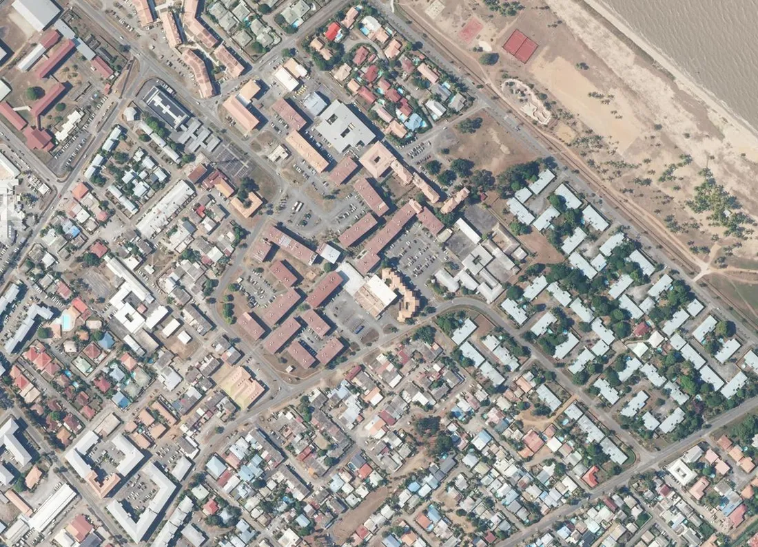 Orthophotographie aérienne du centre de Kourou, en Guyane : barres de logements collectifs, lotissements bas et front de mer