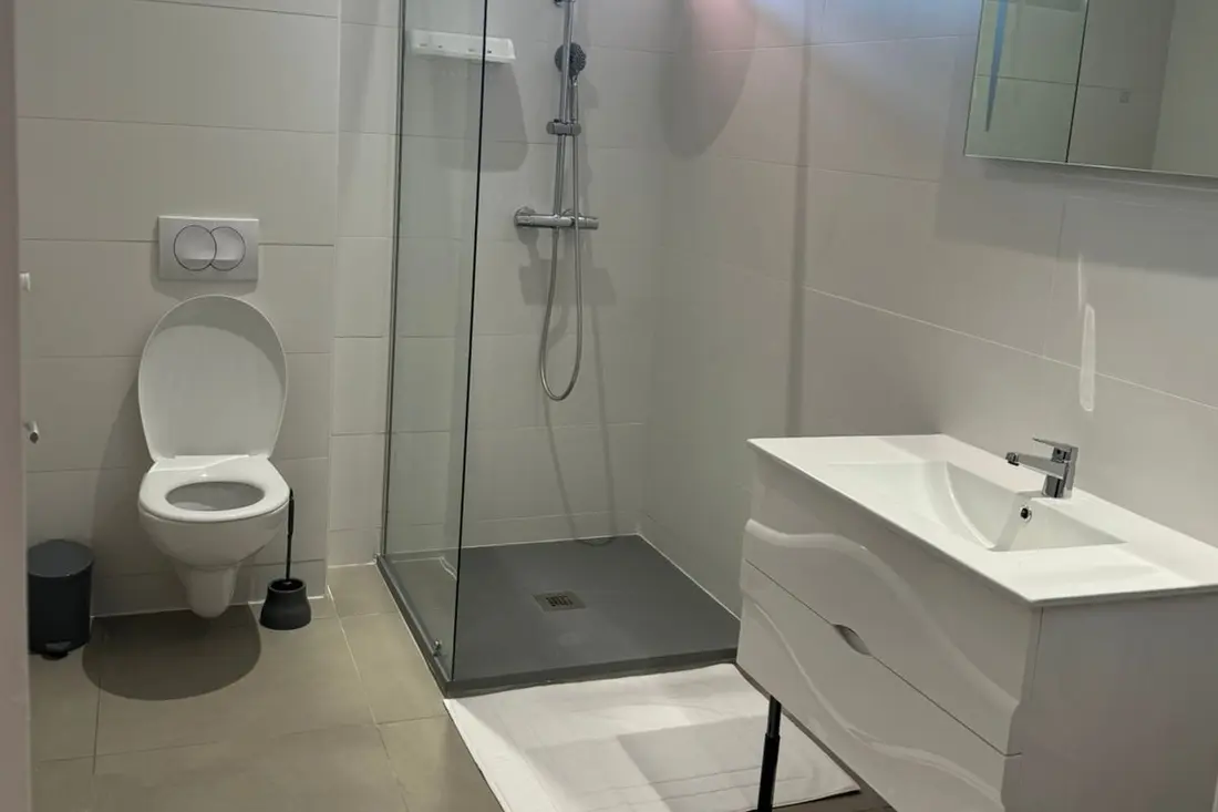 Salle d’eau d’un logement de la Résidence Francis : vasque sur plan bois, paniers de rangement rayés et serviettes pliées