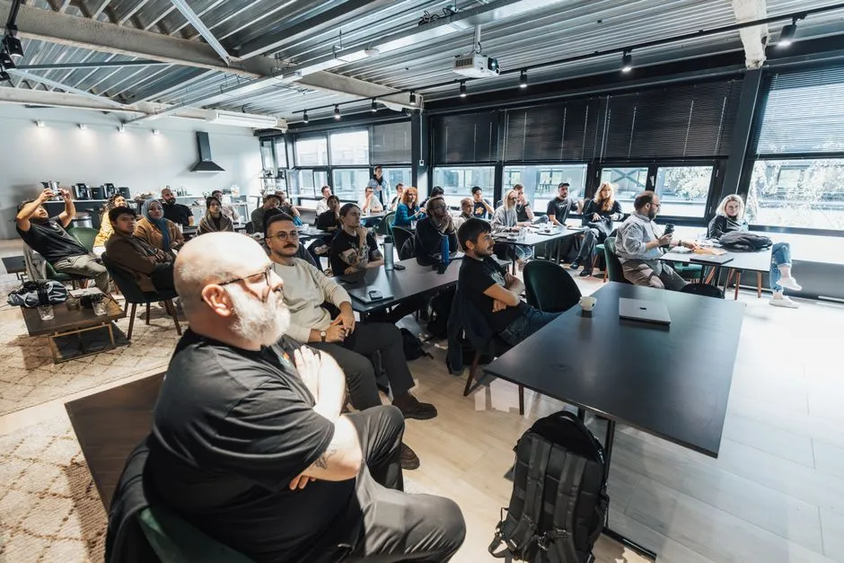 Groupe de participants assis en session de formation dans une salle de réunion lumineuse équipée d'un vidéoprojecteur et de grandes tables