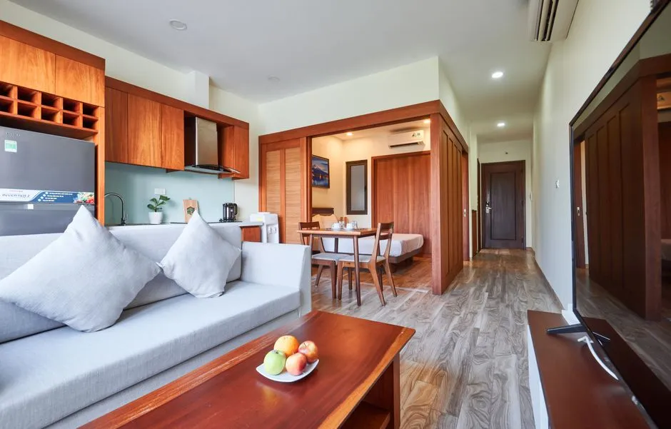 Intérieur d'un appart-hôtel : séjour avec canapé, coin cuisine équipé, table à manger et chambre attenante