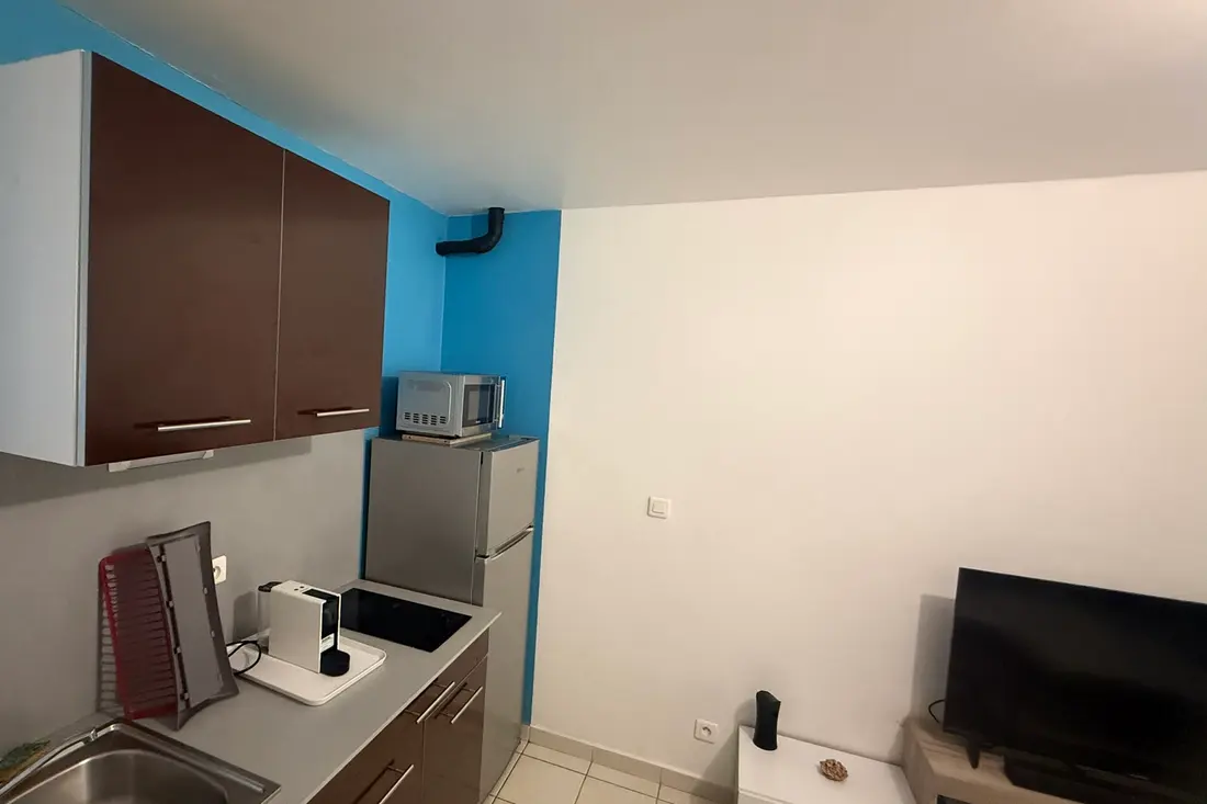 Kitchenette du T2 du Diamant Cayennais à Baduel, mur bleu et réfrigérateur