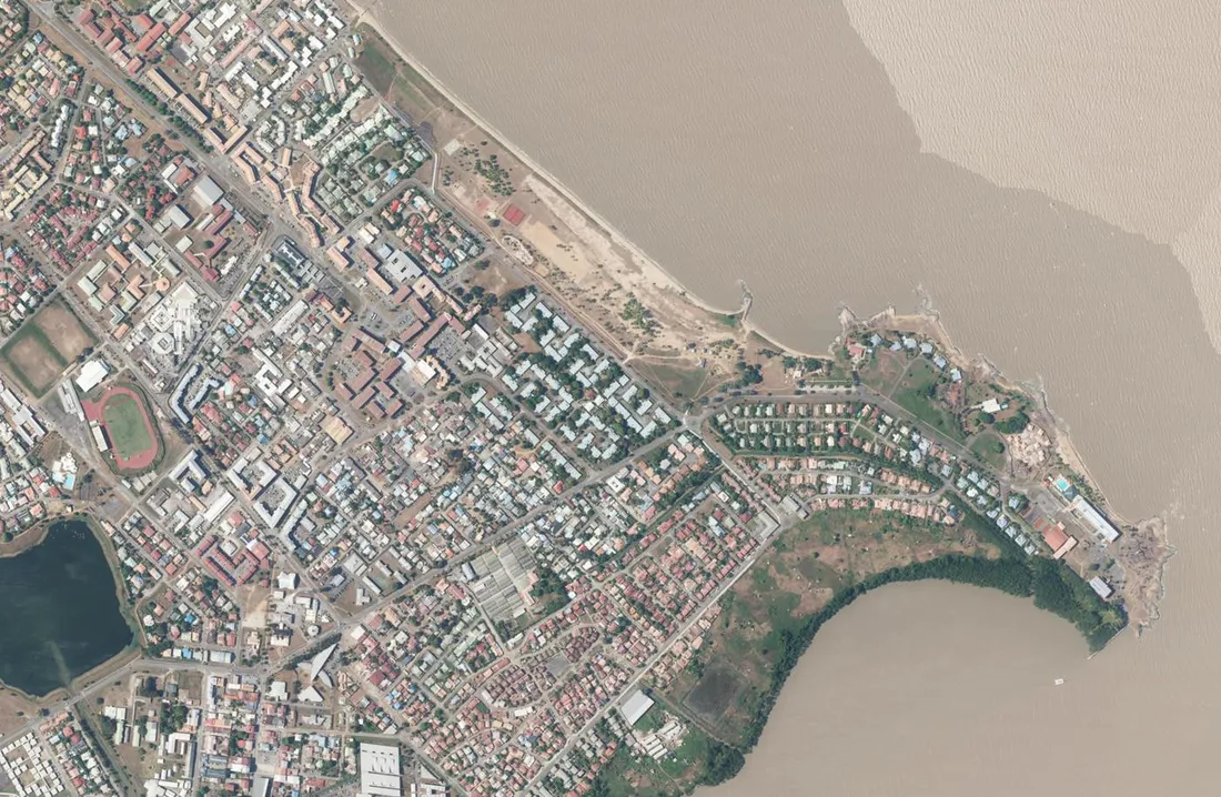 Orthophotographie aérienne verticale de Kourou en Guyane : le centre-ville quadrillé, le front de mer sableux et l'embouchure du fleuve Kourou aux eaux ocre