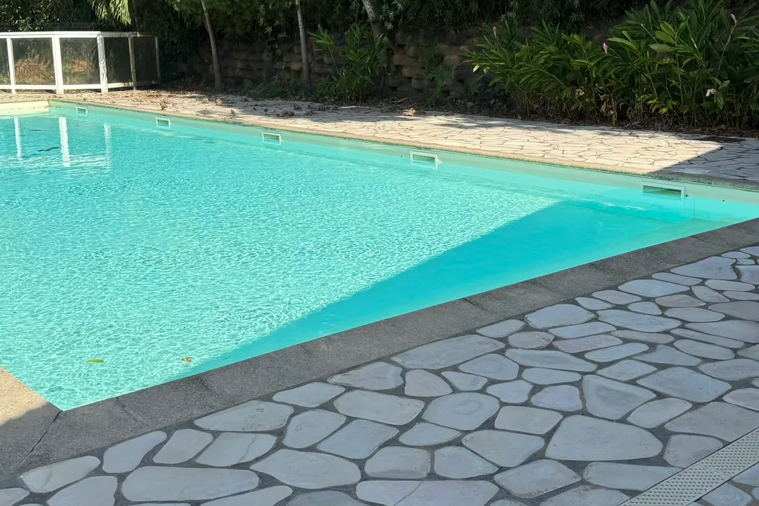Piscine de la résidence du Diamant Cayennais : bassin bordé d’opus incertum clair, végétation dense en fond
