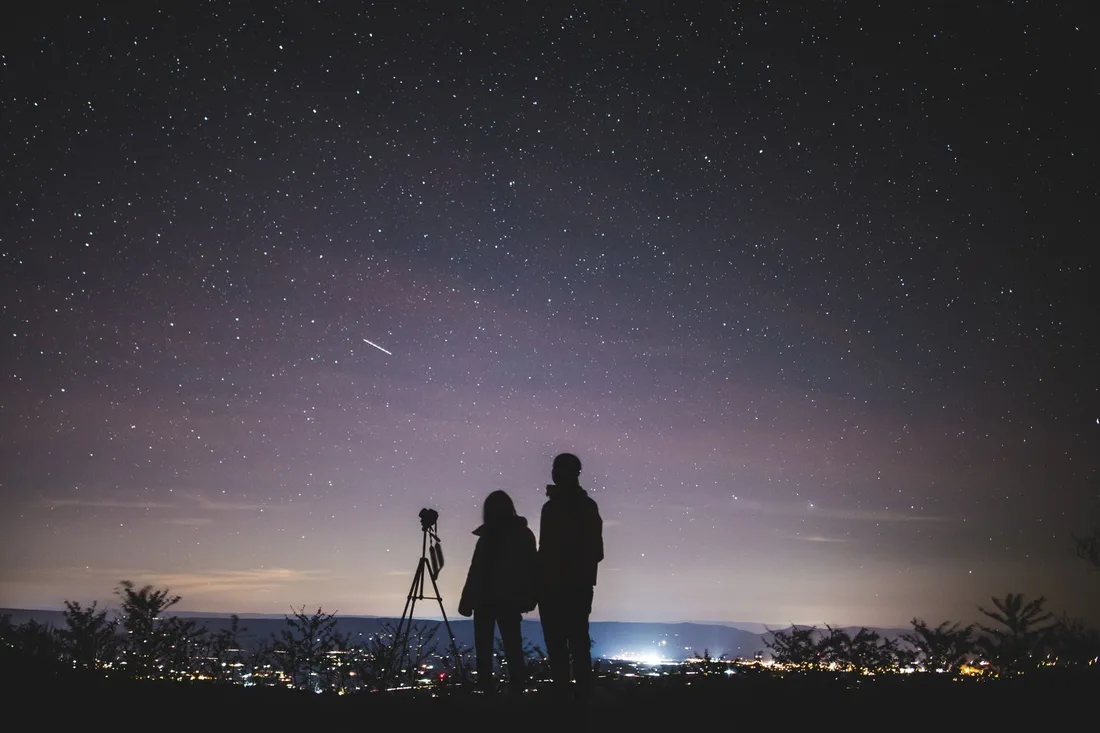 Deux personnes assises observant ensemble un ciel étoilé