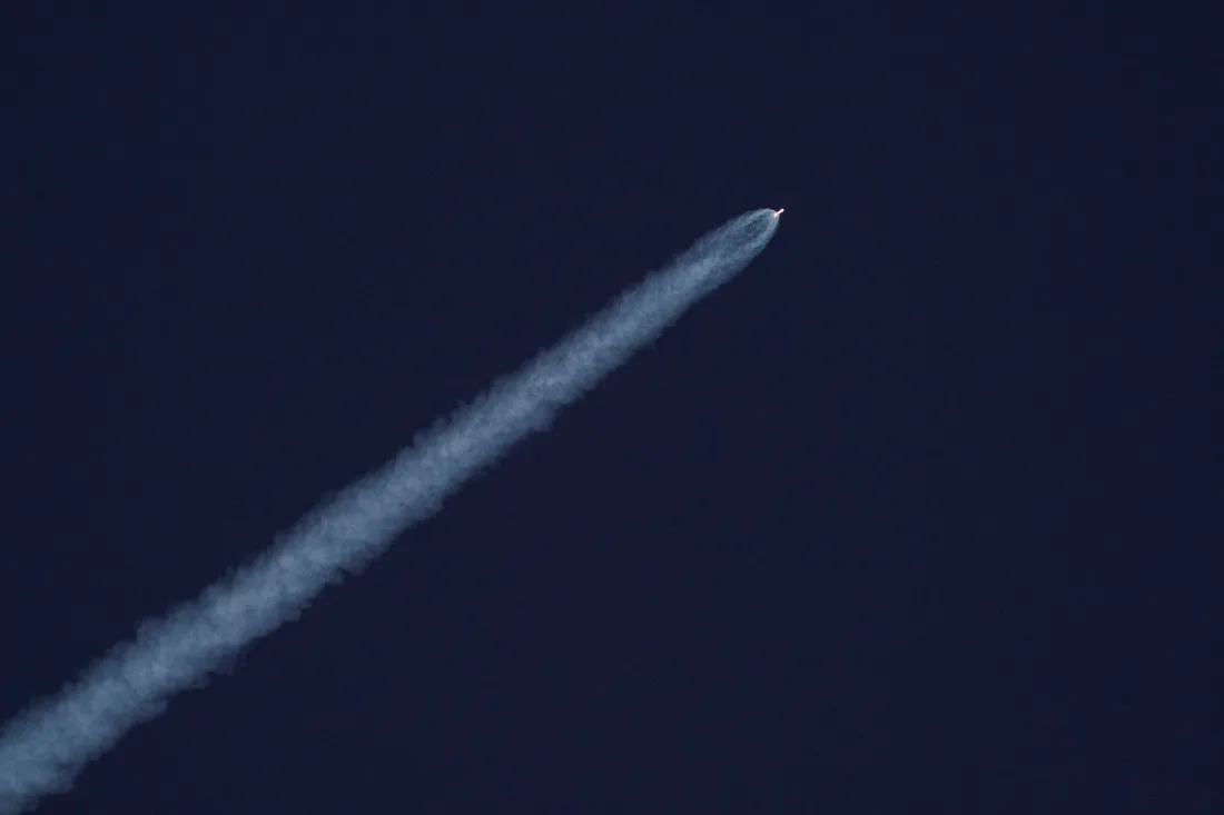 Fusée en ascension laissant une traînée de fumée blanche dans un ciel bleu de jour