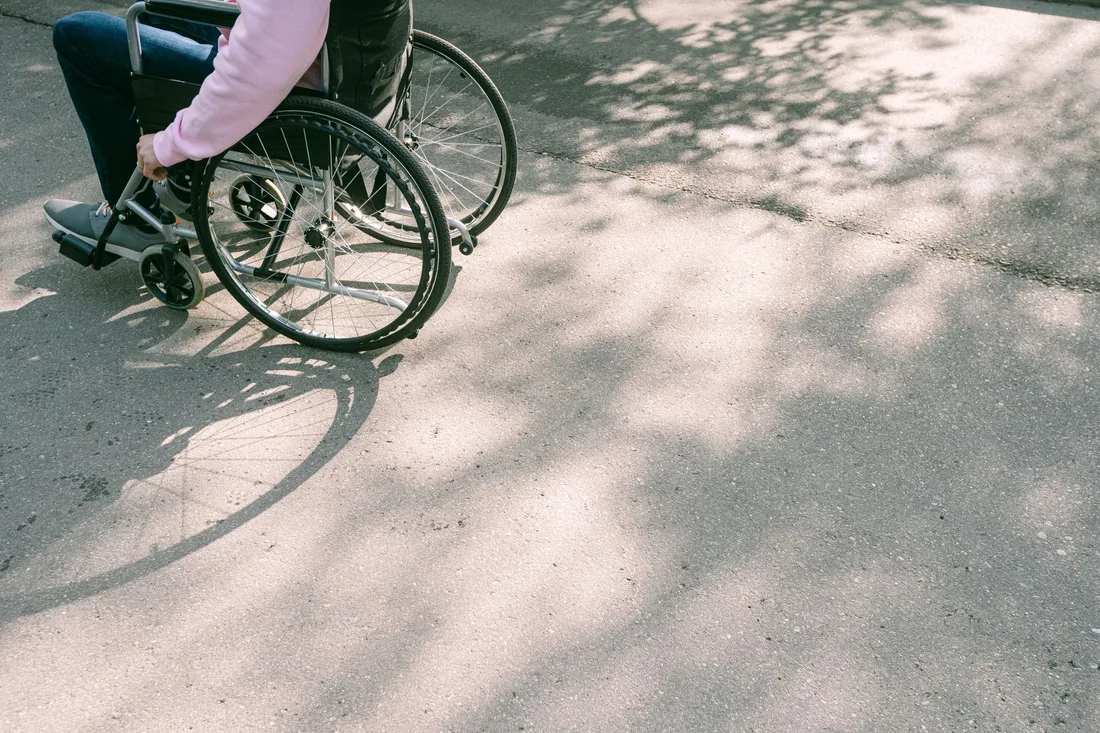 Personne en fauteuil roulant progressant sur une route ensoleillée