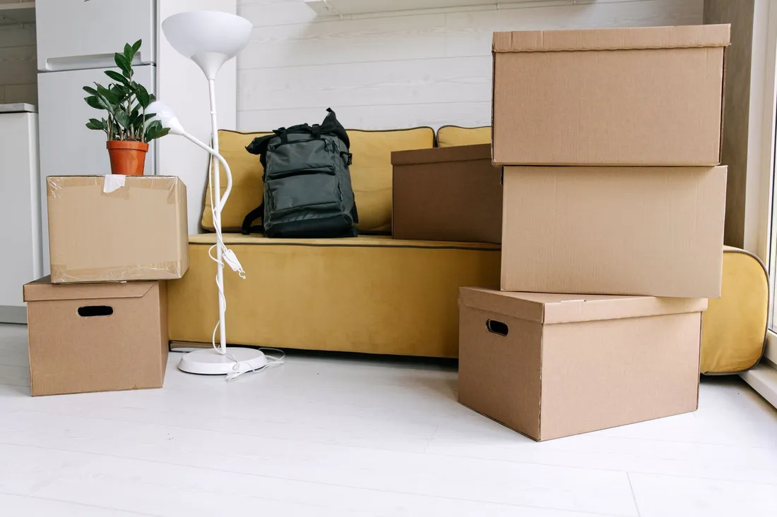 Cartons de demenagement et sac a dos dans un salon lumineux