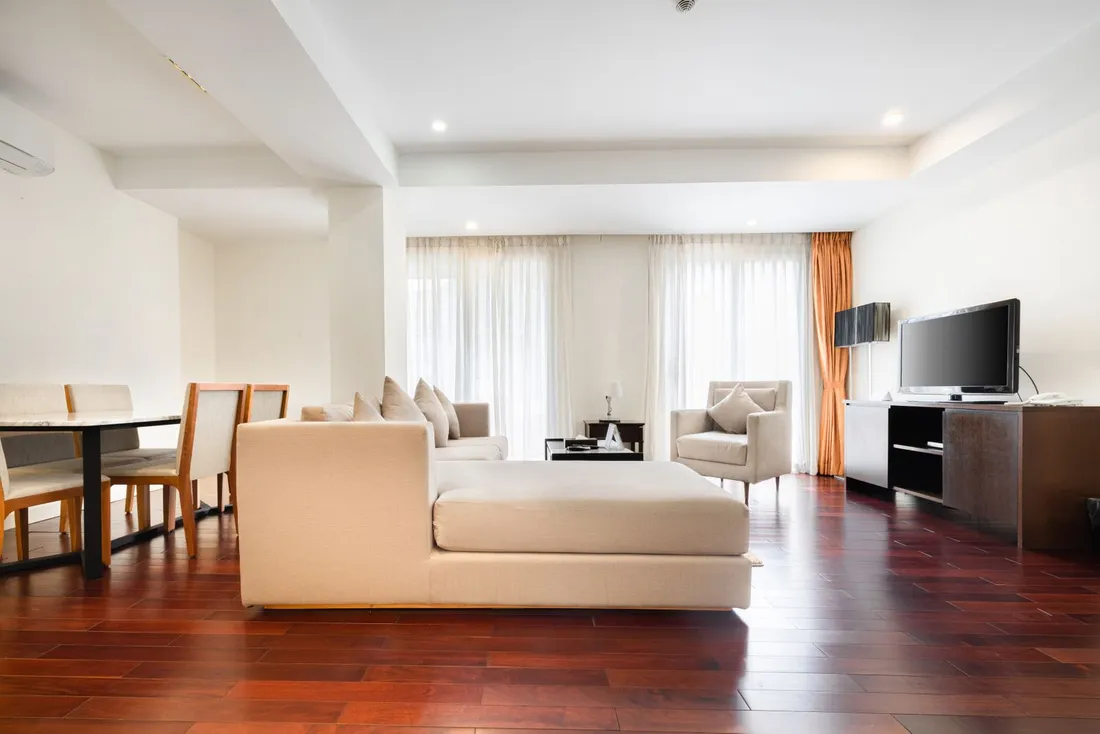 Vaste salon lumineux d'un appartement meublé avec canapé, coin repas, climatisation et parquet, prêt à accueillir des collaborateurs en déplacement