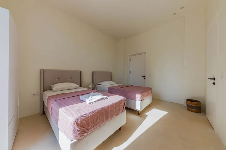 Chambre d'appartement en location équipée de deux lits simples, d'une armoire et d'un ventilateur, prête à accueillir plusieurs collègues