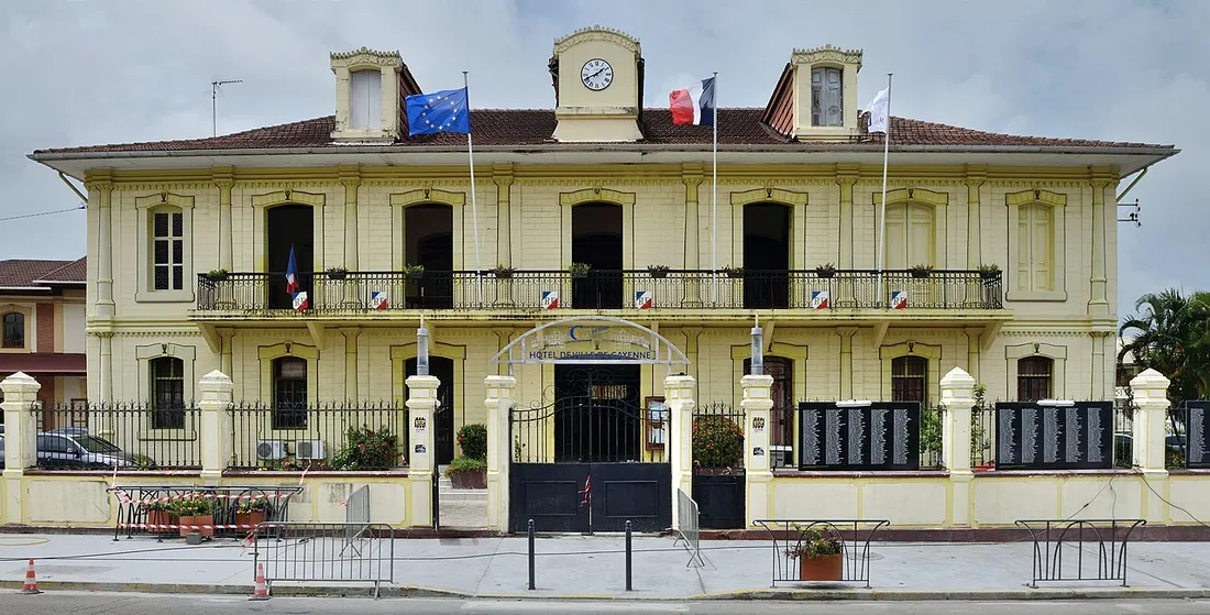 Façade jaune de l'hôtel de ville de Cayenne, avec ses balcons en fer forgé et son horloge, dans le centre administratif de la Guyane