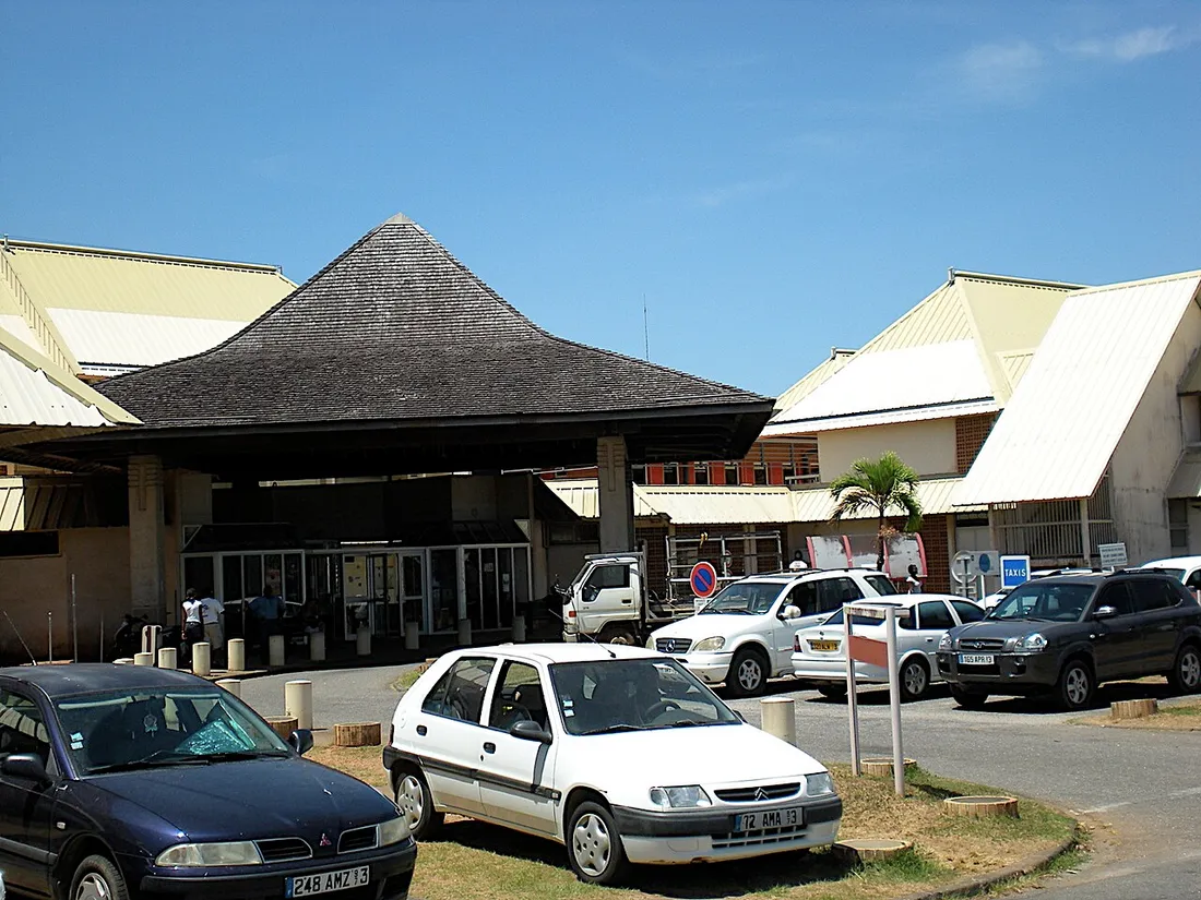 Entrée du centre hospitalier Andrée-Rosemon à Cayenne, en Guyane, avec son auvent en bois à toit pentu et le parking des consultations externes