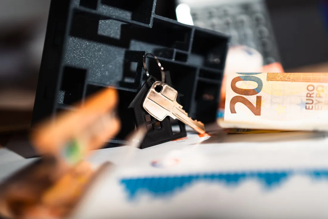 Clés de logement sur un porte-clés maison, avec un billet de 20 euros et un graphique