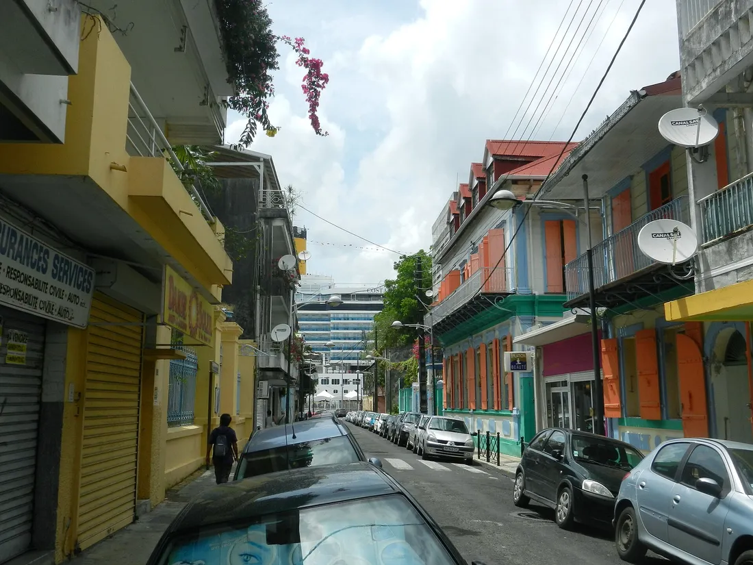 Rue commercante coloree du centre-ville de Pointe-a-Pitre en Guadeloupe, avec maisons creoles et voitures stationnees