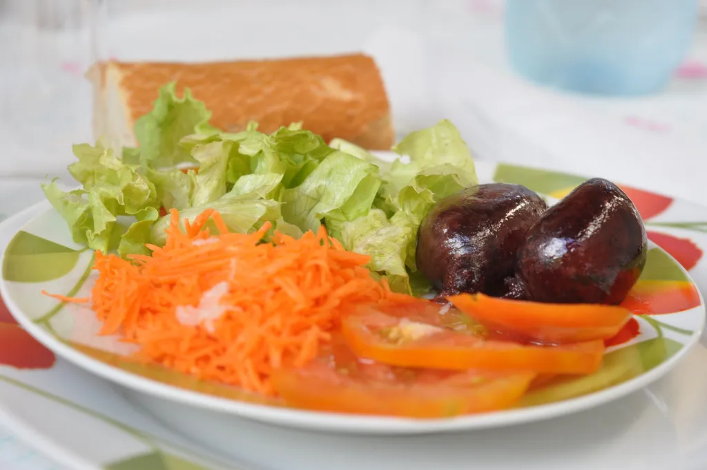 Assiette de boudin créole guadeloupéen servi avec crudités, carottes râpées, tomates et morceau de pain