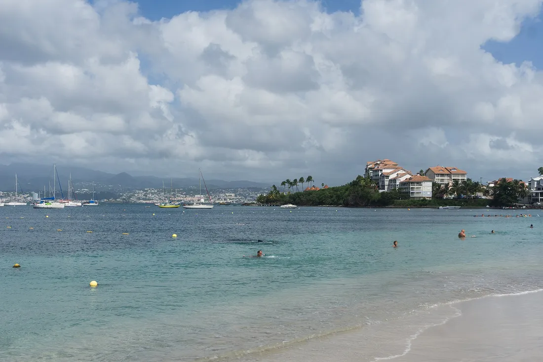 Front de mer des Trois-Îlets en Martinique, plage et voiliers avec les hauteurs de l'île en arrière-plan
