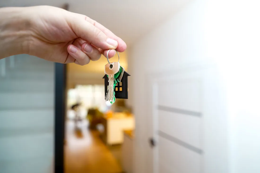 Main tenant un trousseau de clés à l'entrée d'un logement neuf