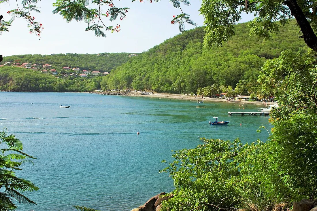 Baie et plage de sable sombre de Malendure à Bouillante, sur la côte sous-le-vent de Basse-Terre en Guadeloupe, adossée aux collines volcaniques verdoyantes