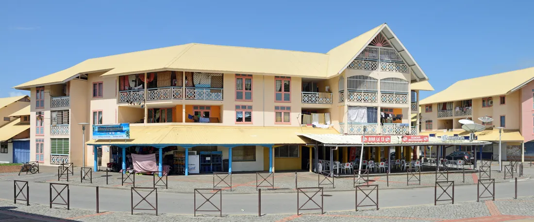 Immeuble d'habitation de trois niveaux avec balcons et commerces en rez-de-chaussée, dans le centre de Kourou, en Guyane