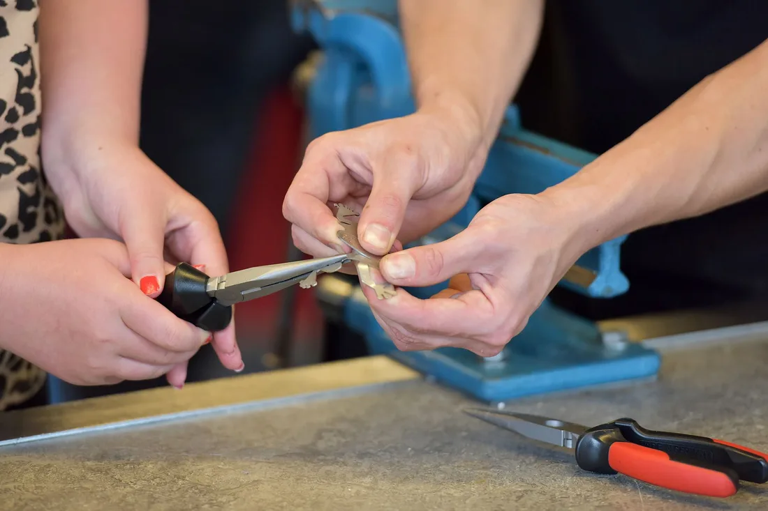 Gros plan sur des mains utilisant une pince dans un atelier