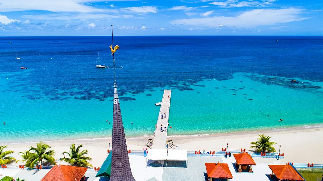 Vue aerienne de la baie des Anses-d'Arlet en Martinique avec son ponton, son eau turquoise et le clocher de l'eglise, site prise tres souvent en drone