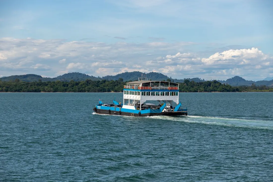 Navette maritime a passagers traversant des eaux calmes vers une cote verdoyante tropicale