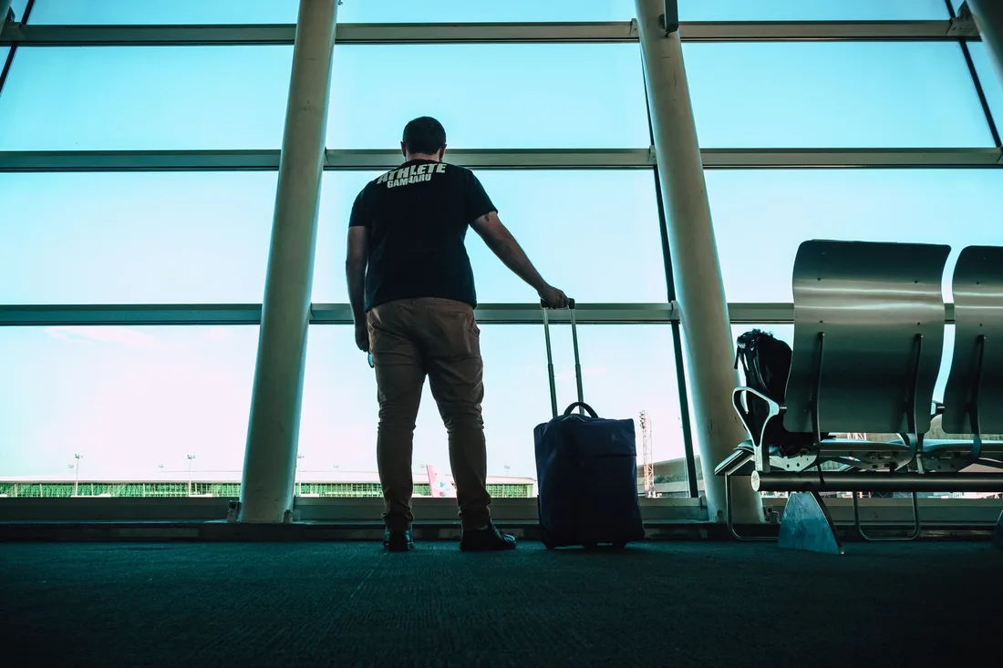 Voyageur avec ses bagages patientant dans un hall d'aéroport