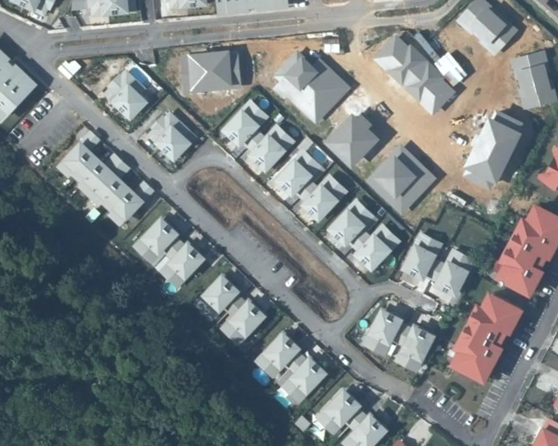 Vue aérienne verticale de la Résidence Cœur d'Ébène à Rémire-Montjoly : deux alignements de petits immeubles à toiture claire de part et d'autre de la rue Wacapou, avec une longue bande centrale non bâtie servant de stationnement