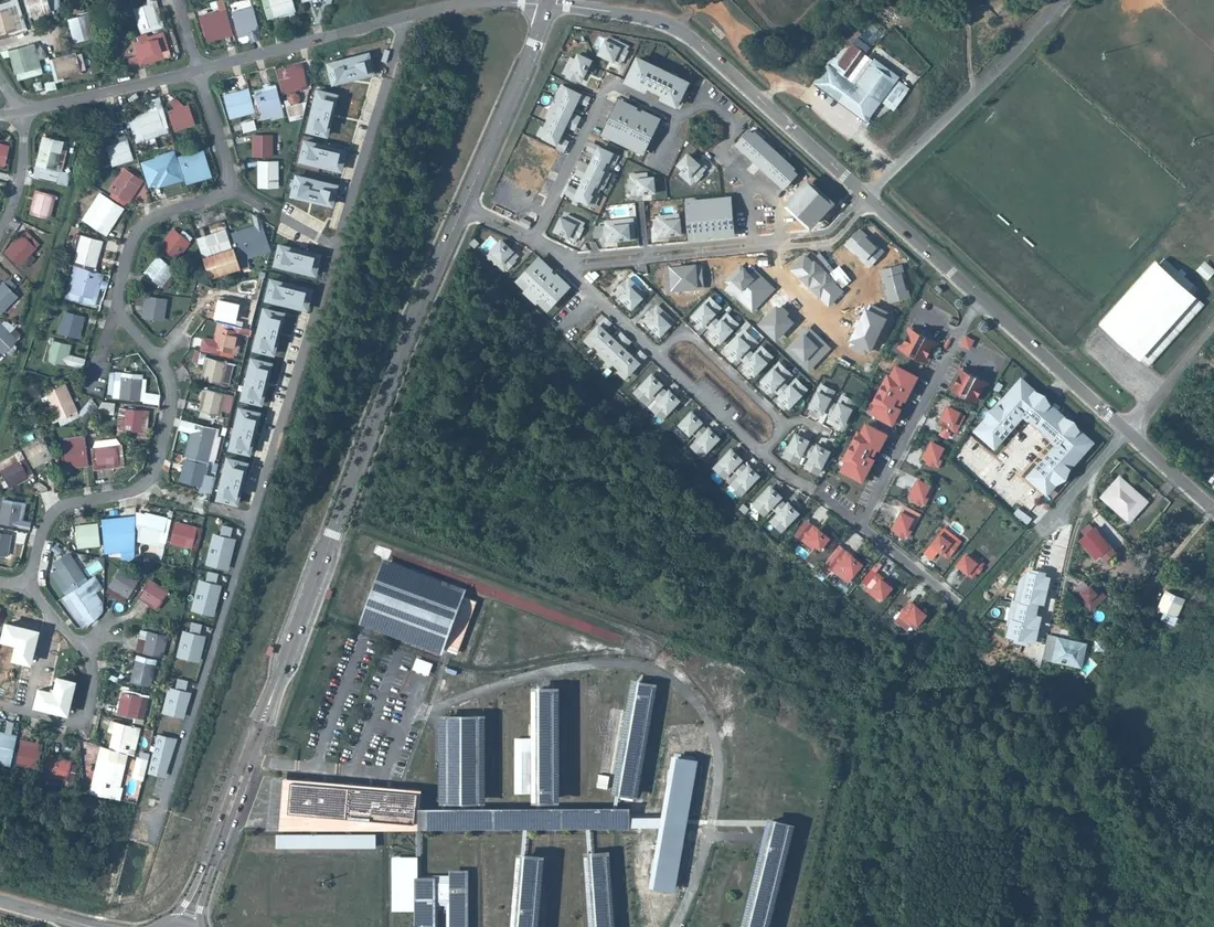 Vue aérienne du quartier de Rémire-Montjoly autour de la Résidence Cœur d'Ébène : la résidence en haut à droite, un lotissement pavillonnaire à l'ouest, une bande boisée au centre et un établissement scolaire avec sa piste d'athlétisme au sud