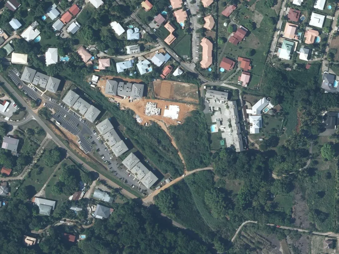Vue aérienne de l'îlot de la Résidence La Perle Noire à Rémire-Montjoly : petits collectifs à toitures claires, parkings en épi et parcelle en chantier, entre rue Sainte-Thérèse et route des Plages