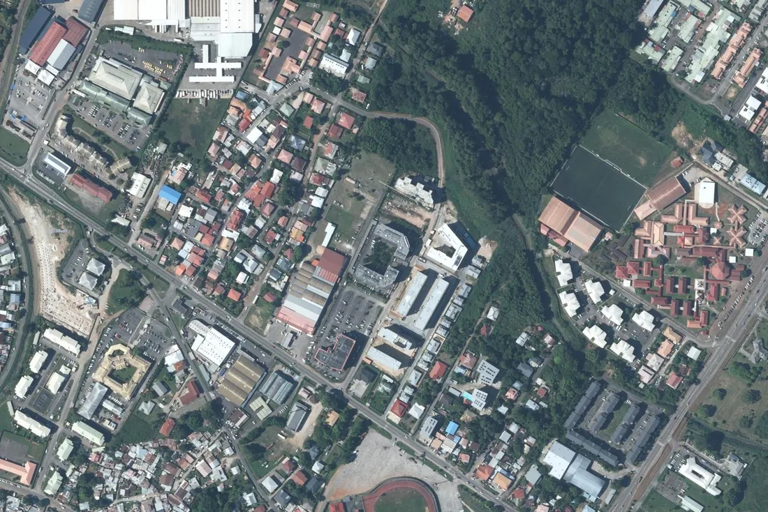 Vue aérienne du quartier Baduel à Cayenne, de part et d'autre de la route de Baduel, avec les équipements sportifs et les lotissements du secteur