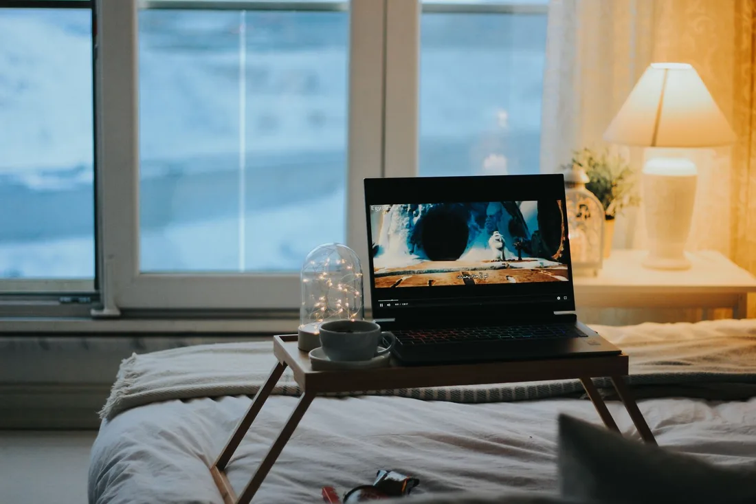Ordinateur portable posé sur une tablette de lit, ambiance calme