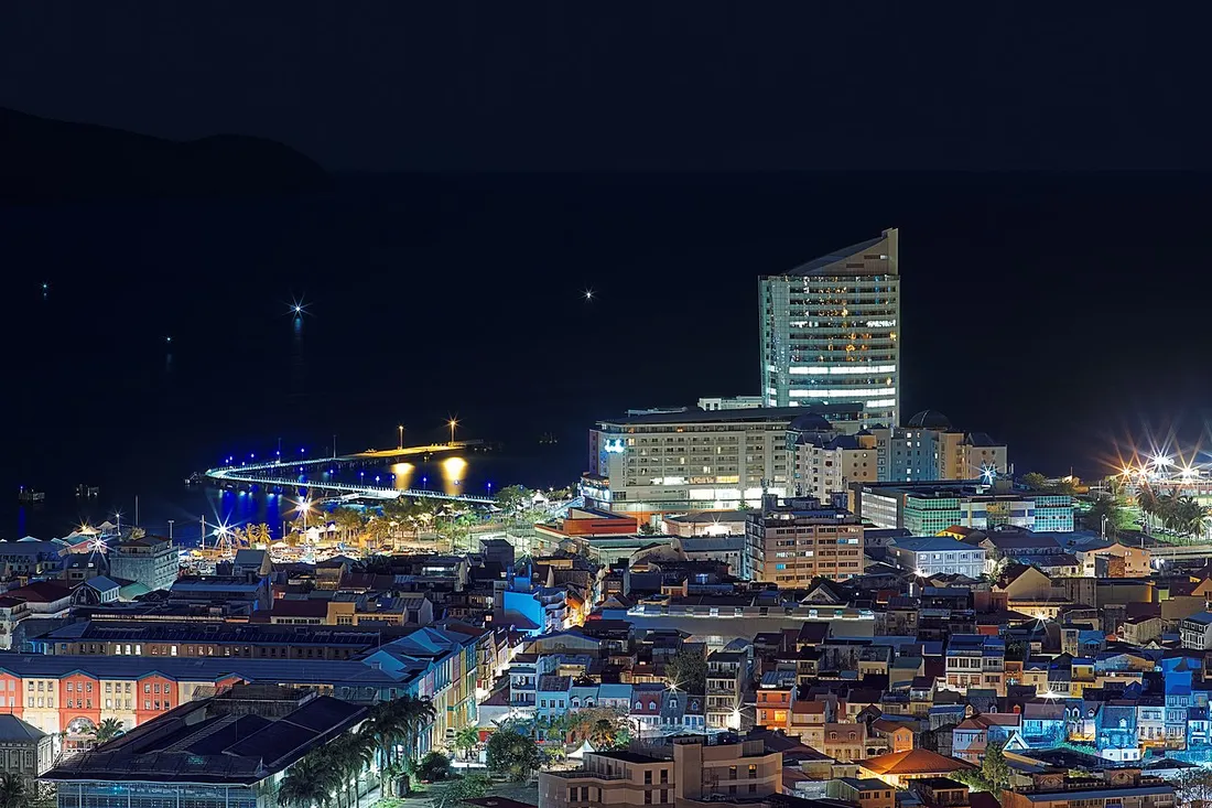 Vue nocturne du centre-ville de Fort-de-France en Martinique, ses toits résidentiels et la tour Pointe Simon, illustrant le marché immobilier local