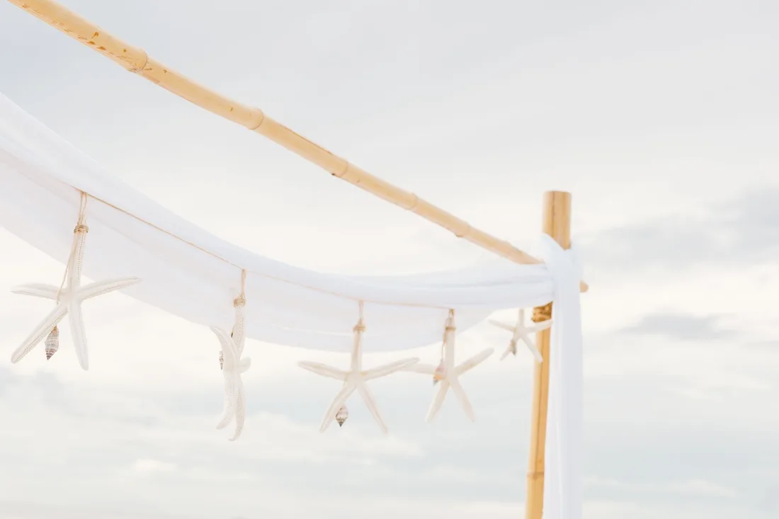 Arche de bambou décorée d'étoiles de mer sur une plage