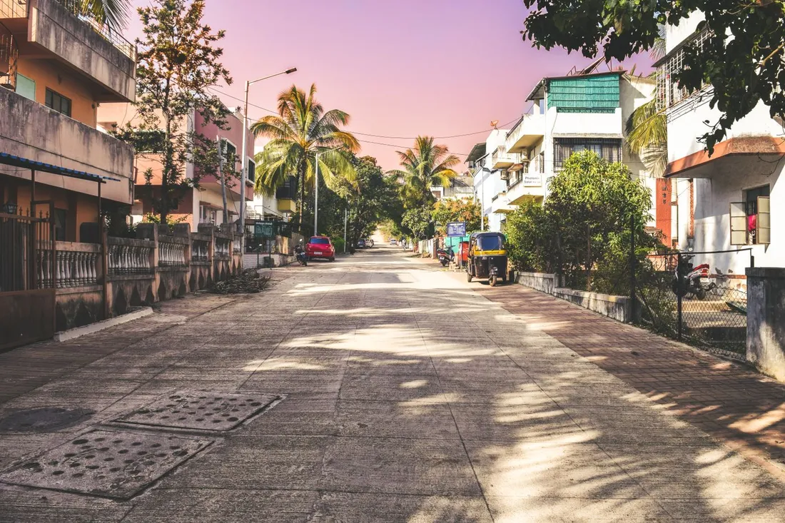 Rue résidentielle tropicale paisible, bordée de palmiers et de maisons, sous un ciel dégagé