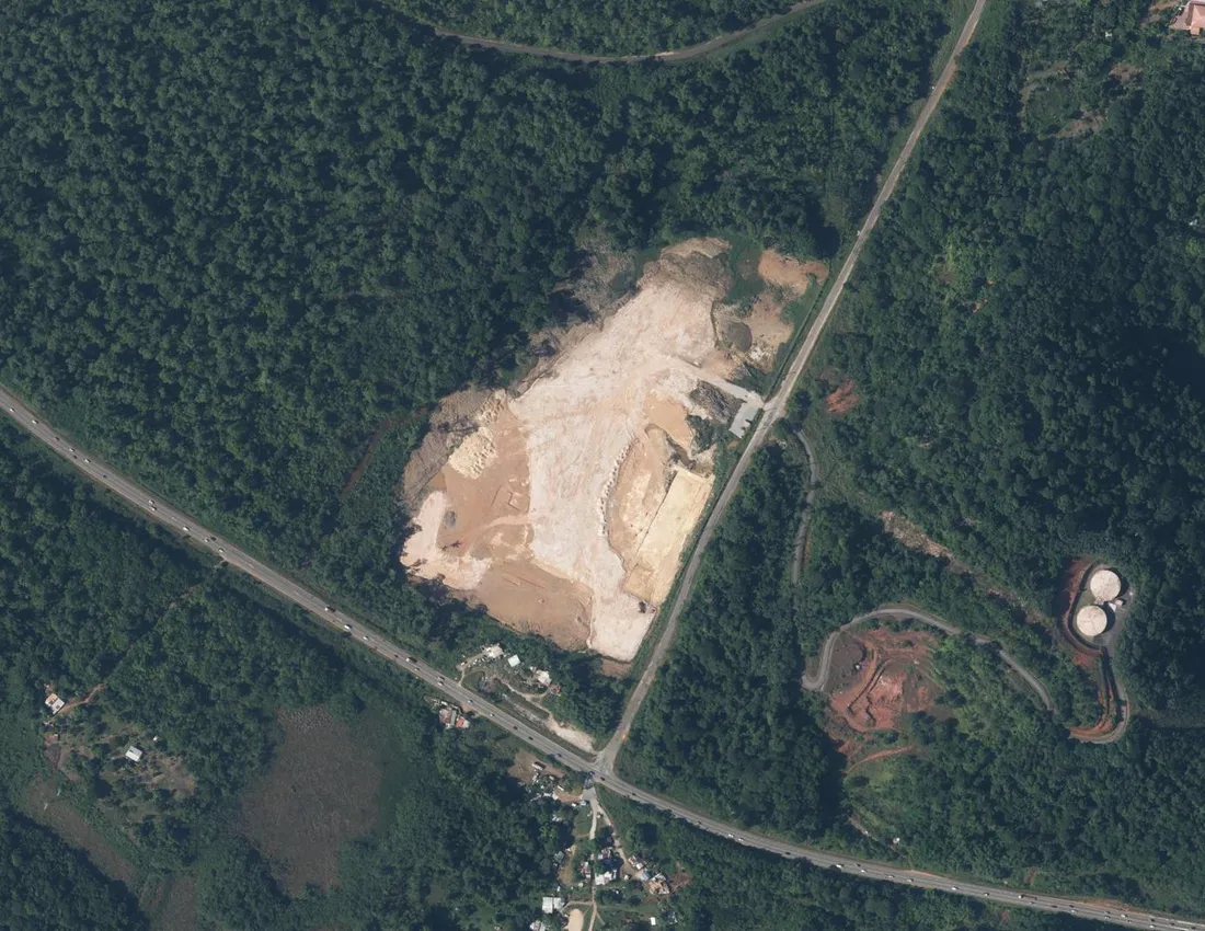 Vue aérienne verticale d'une vaste plateforme de terrassement défrichée bordée par la RN1 et la forêt, au lieu-dit Larivot à Matoury en Guyane