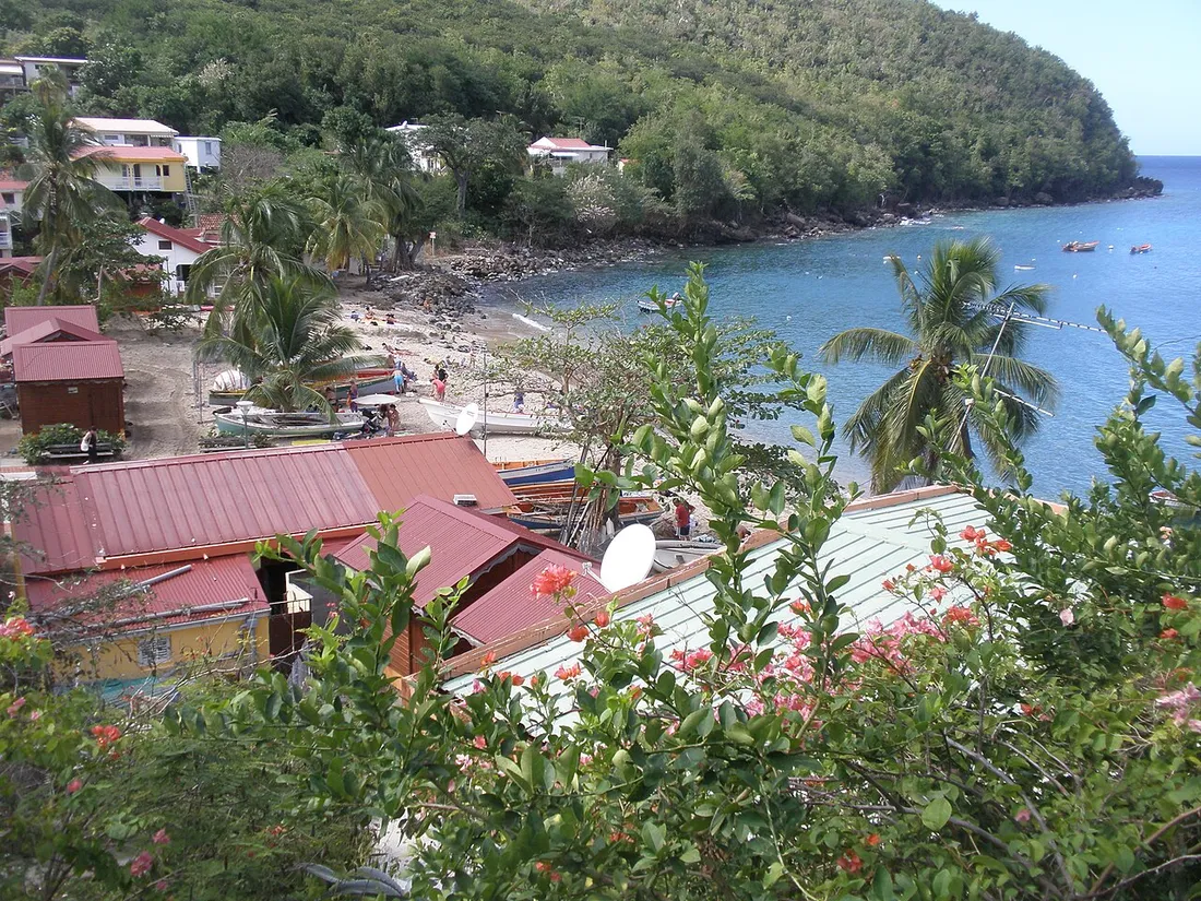 Plage et baie de l'Anse Dufour aux Anses-d'Arlet en Martinique, avec barques de pêche, hameau aux toits rouges et eaux abritées propices au snorkeling