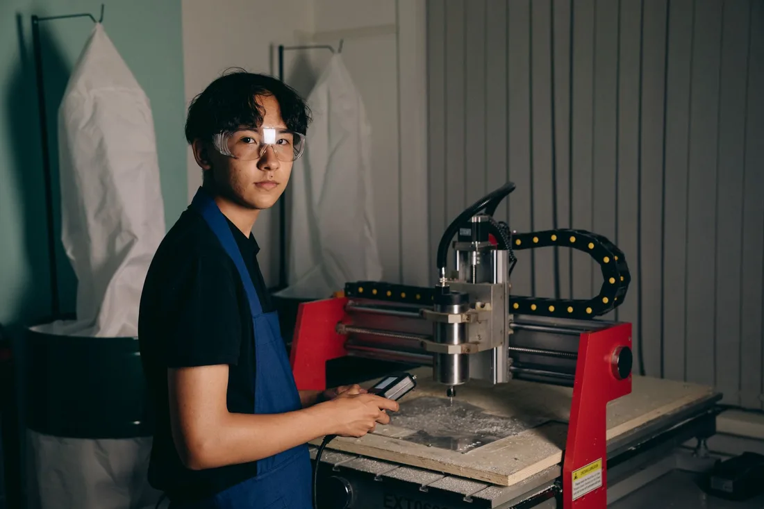 Jeune opérateur conduisant une machine à commande numérique, lunettes de sécurité
