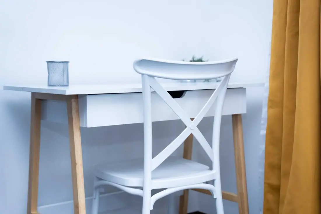 Coin bureau du Baduel Smart Studio : table et chaise blanches devant un rideau jaune moutarde